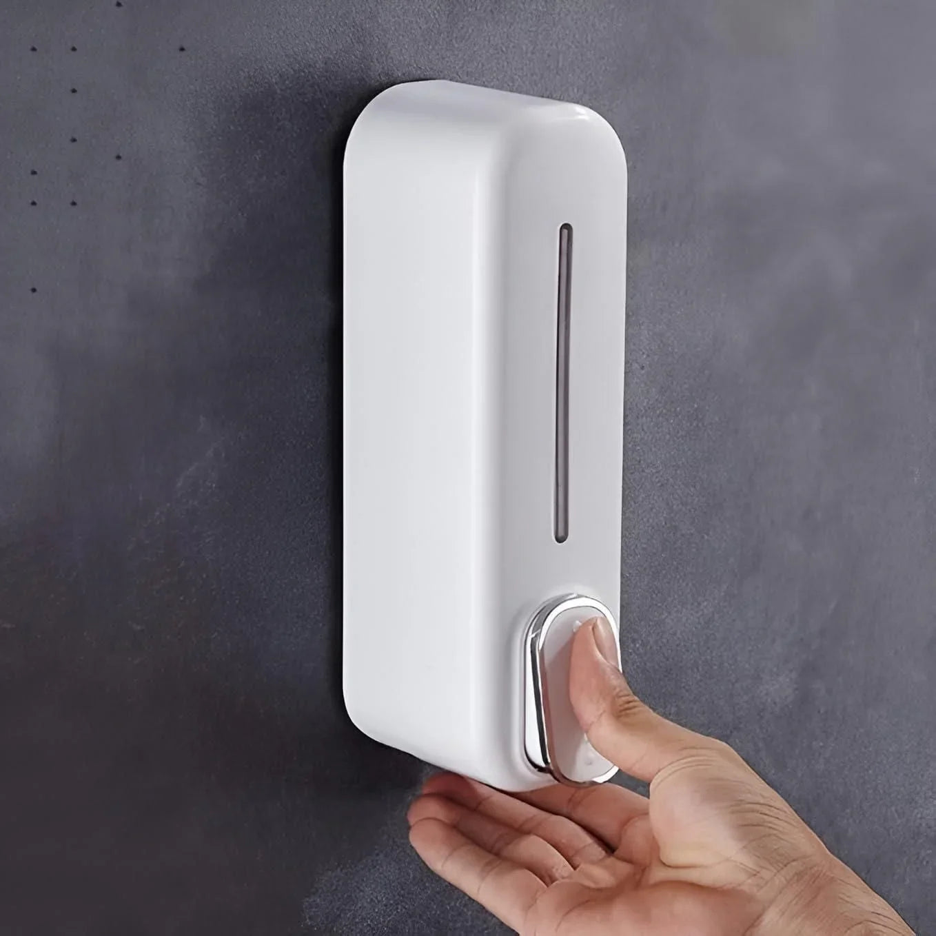 White wall mounted soap dispenser with push button being used on dark wall