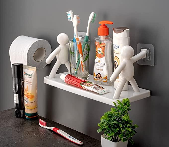 White wall hanging bathroom shelf with two stick figure brackets holding toothbrushes soap and toothpaste