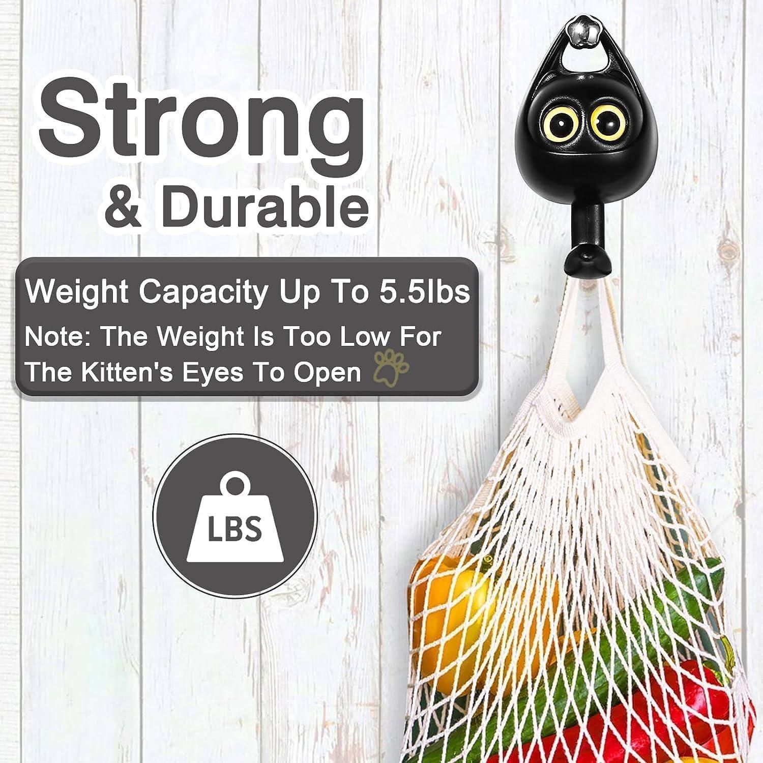 Black cat wall hook with yellow eyes holding a produce bag on white wood background cute wall key hooks