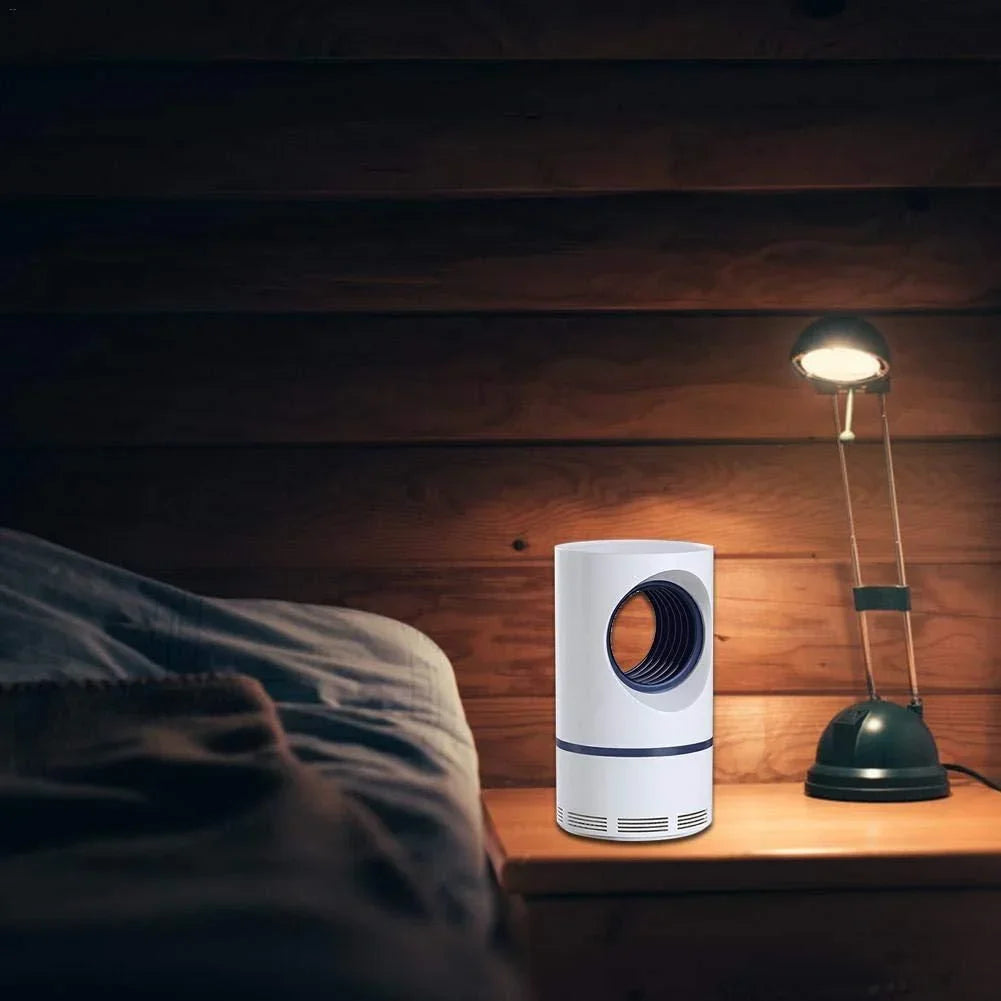 White LED mosquito killer lamp placed on wooden bedside table near lamp in dimly lit room